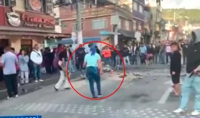 La mujer de azul y de espaldas, confrontado a los encapuchados