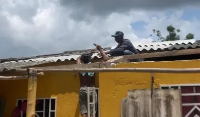 Dos personas aseguran el techo de sus viviendas. 