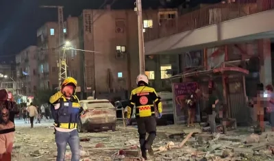 Integrantes de equipos de emergencia, bomberos y policía, trabajan en el área donde un proyectil iraní.