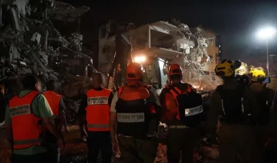 Integrantes de los cuerpos de emergencia junto a un edificio destruido por un misil iraní en Tel Aviv.