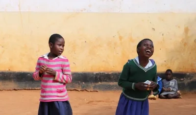 Dos estudiantes con discapacidad visual juegan y ríen durante el recreo.