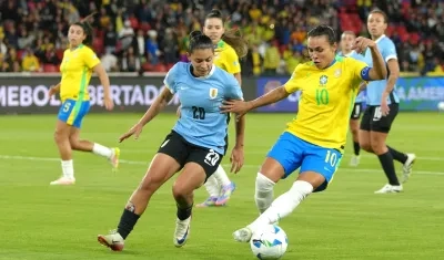 Marta, de Brasil, disputa el balón con Angela Gómez, de Uruguay.
