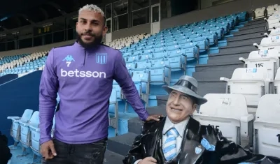 Duván Vergara posa junto a una estatua de Carlos Gardel, en una de las graderías del estadio de Racing. 