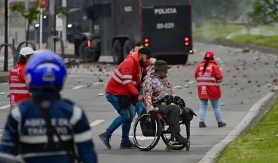 Gestor de convivencia acompañando a una persona en silla de ruedas este viernes, durante protesta en Bogotá.