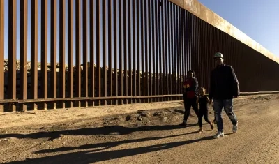 Familia caminando junto al muro fronterizo en Yuma, Arizona.