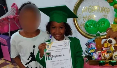 La niña con su diploma de grado y al lado de su hermanito.