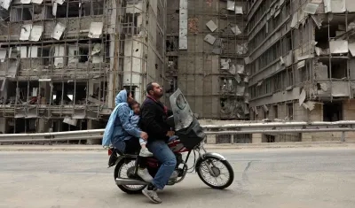 Iraníes pasan en motocicleta frente al hospital Gandhi, destruido en Teherán, Irán.