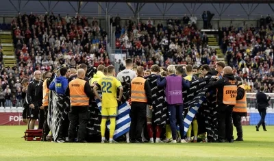Jugadores de Dinamarca y Ucrania alrededor de Christian Eriksen después de que se desplomara.