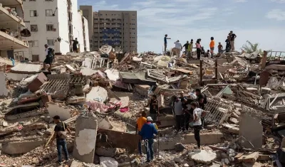 Personas caminan entre escombros de edificios afectado por terremotos