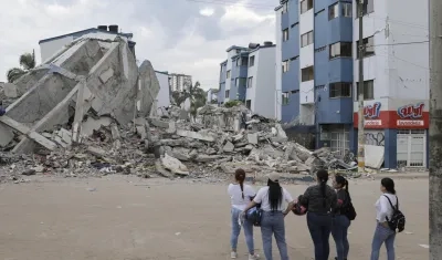Personas observan los escombros de un edificio afectado por el terremoto en Pereira. 