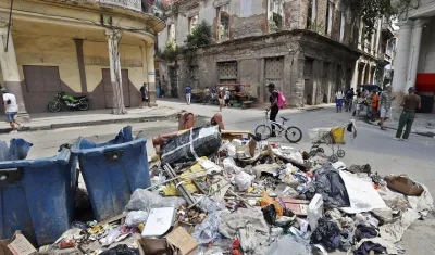 Personas caminan frente a basura acumulada por la falta de combustible para su recolección.