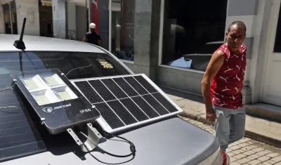 Hombre observa un panel solar que suministra energía a una lámpara.
