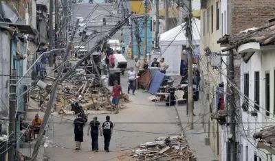 Personas caminan frente a edificaciones afectadas por el terremoto en Pereira.