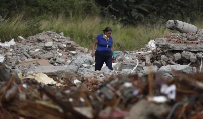 Una persona busca en los escombros de edificios colapsados.