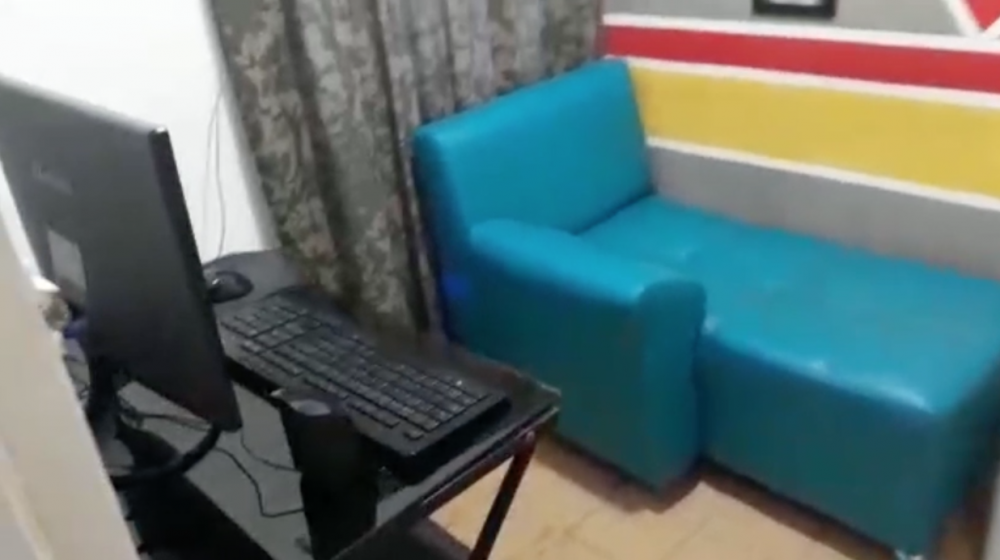 Uno de los cubículos o cuarto pequeño con computador, cámara y un sofá.