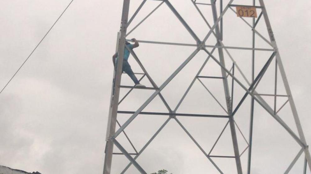 El hombre cuando estaba en la torre de energía antes de ser rescatado.