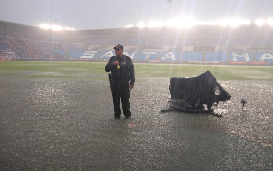 Un policía observa en medio de la tormenta y las cámaras de la transmisión se protegen.