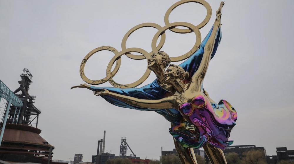 La gente pasa junto a los logotipos de los Juegos Olímpicos de Invierno de Beijing 2022 cerca de la sede del comité organizador de los Juegos Olímpicos de Invierno de Beijing 2022, en el Parque Shougang en Beijing, China.