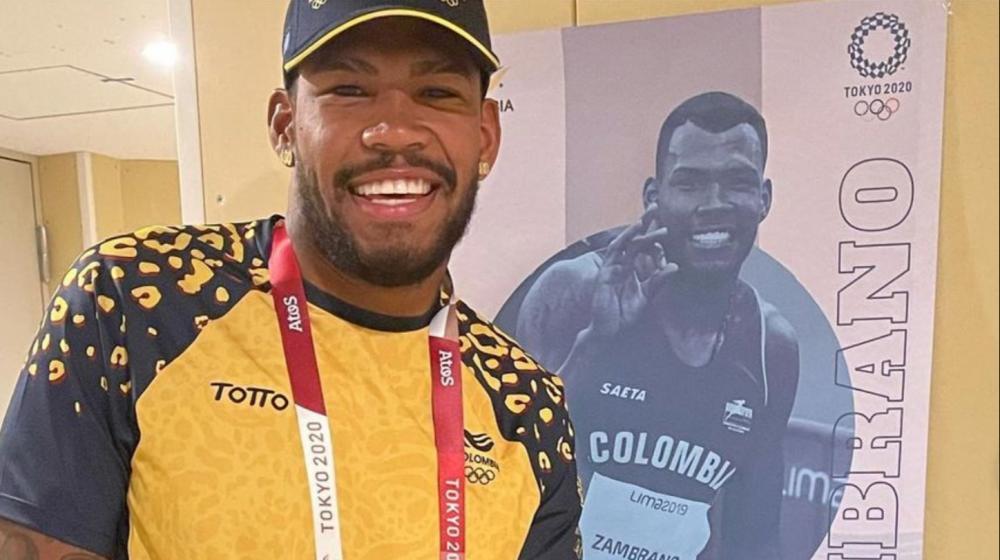 Anthony Zambrano, atleta colombiano, posa al lado de el poster con su rostro. 
