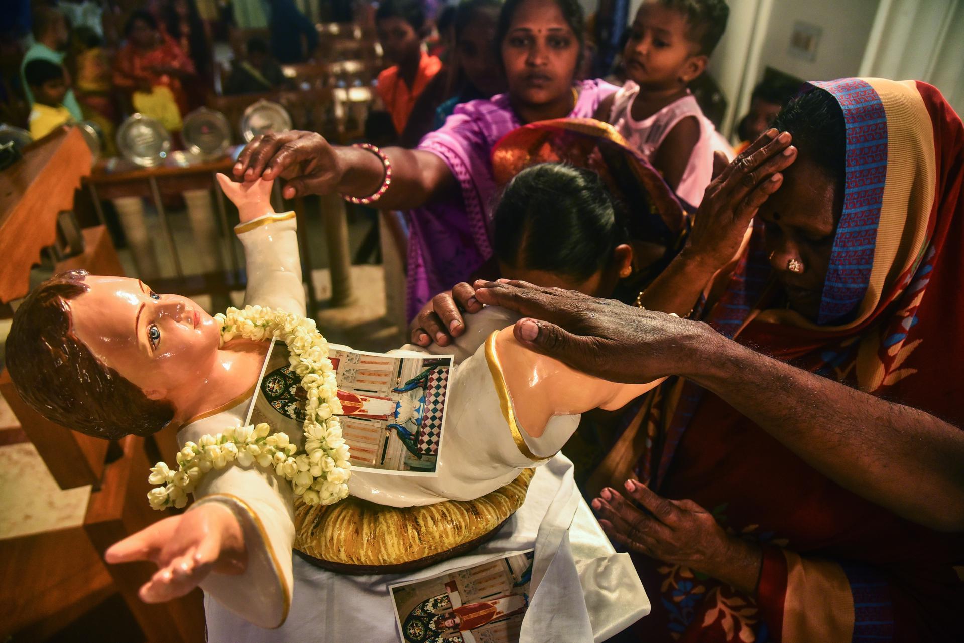 Devotos  tocan la figura del Niño Dios después de la misa de Navidad en la Basílica Catedral de Santhome, en Chennai, India.