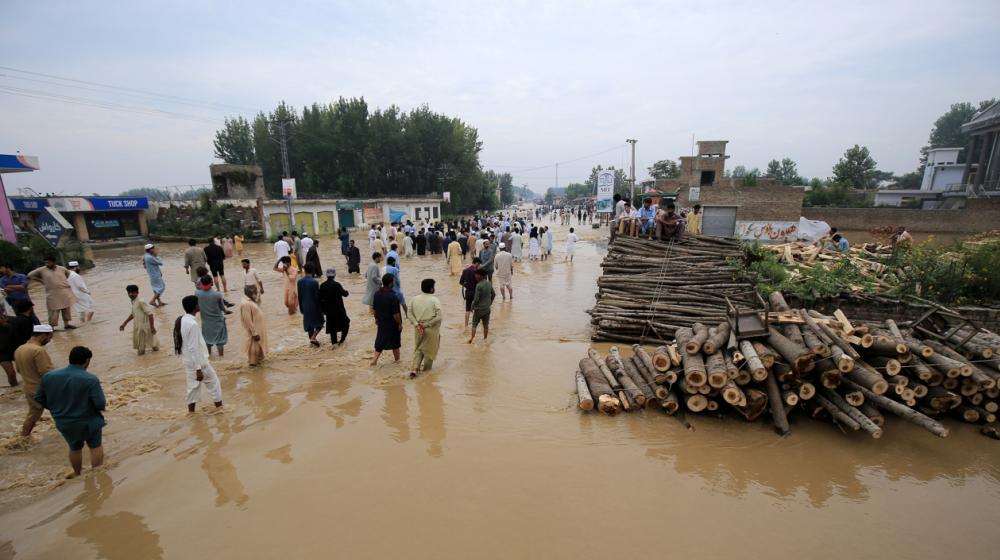 La gente vadea una zona inundada tras las fuertes lluvias en el distrito de Charsadda, provincia de Khyber Pakhtunkhwa, Pakistán.