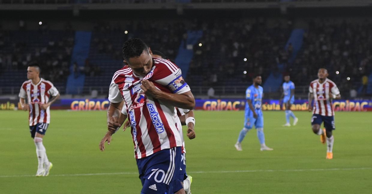 Carlos Bacca celebra besando el escudo tras abrir el marcador, de pena máxima.