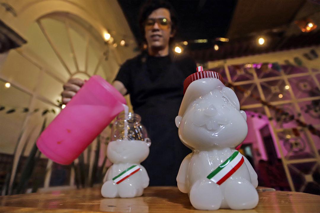 Persona sirviendo un vaso con la imagen de Andrés Manuel López Obrador.