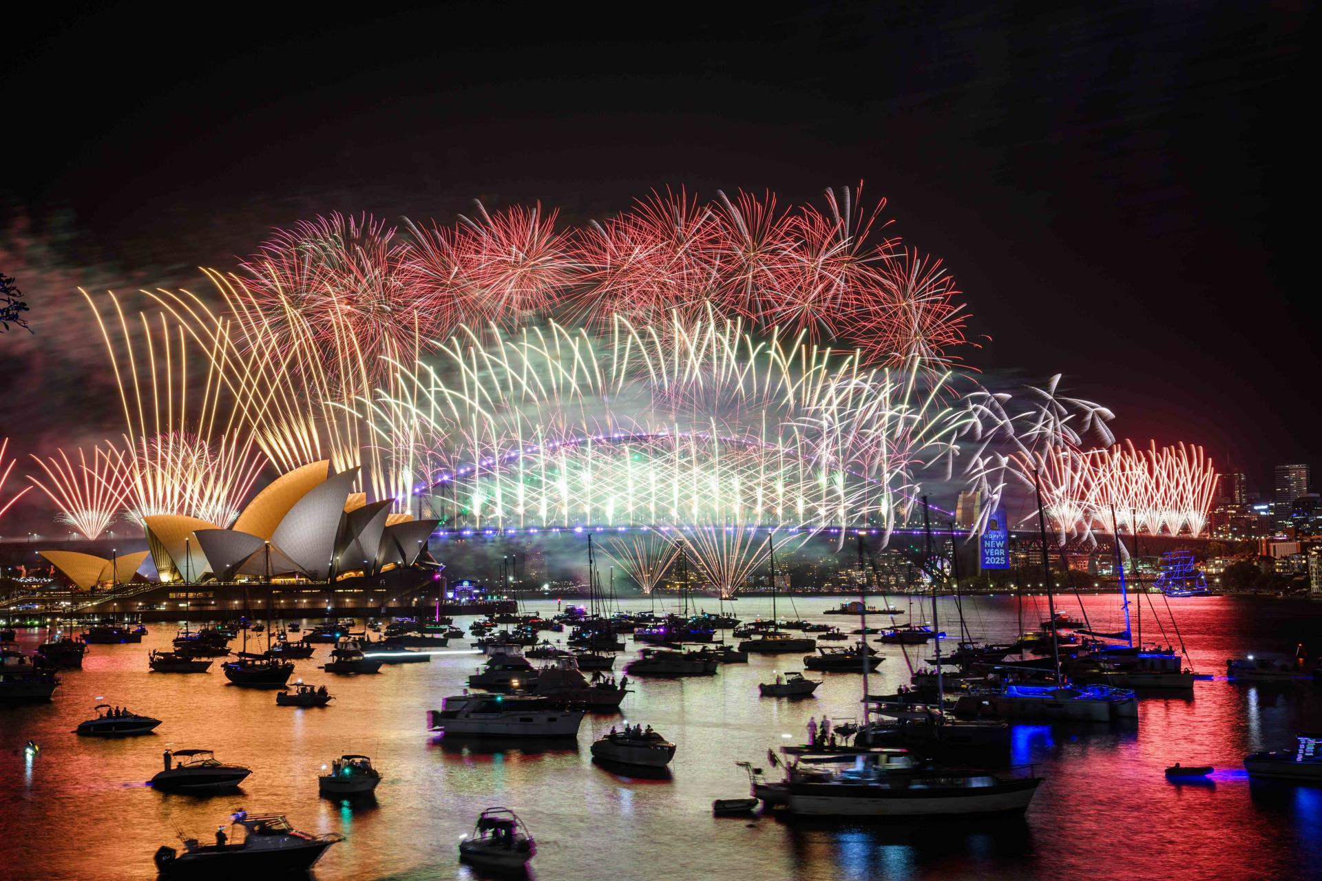 Fuegos artificiales iluminan el cielo sobre la Ópera de Sídney y el Puente del Puerto como parte de las primeras celebraciones.