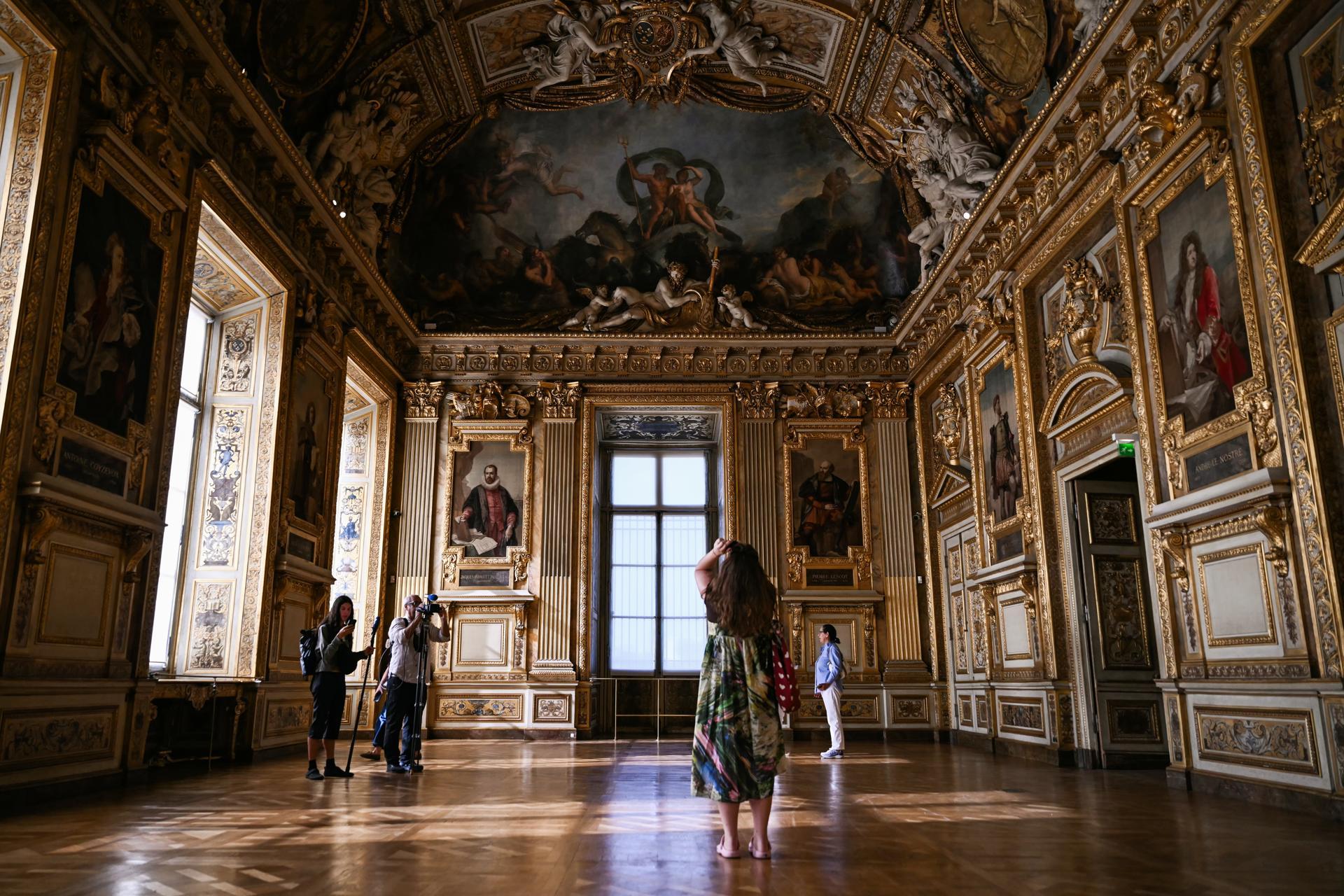 Un grupo de personas recorre la Galería Apolo del Museo del Louvre.