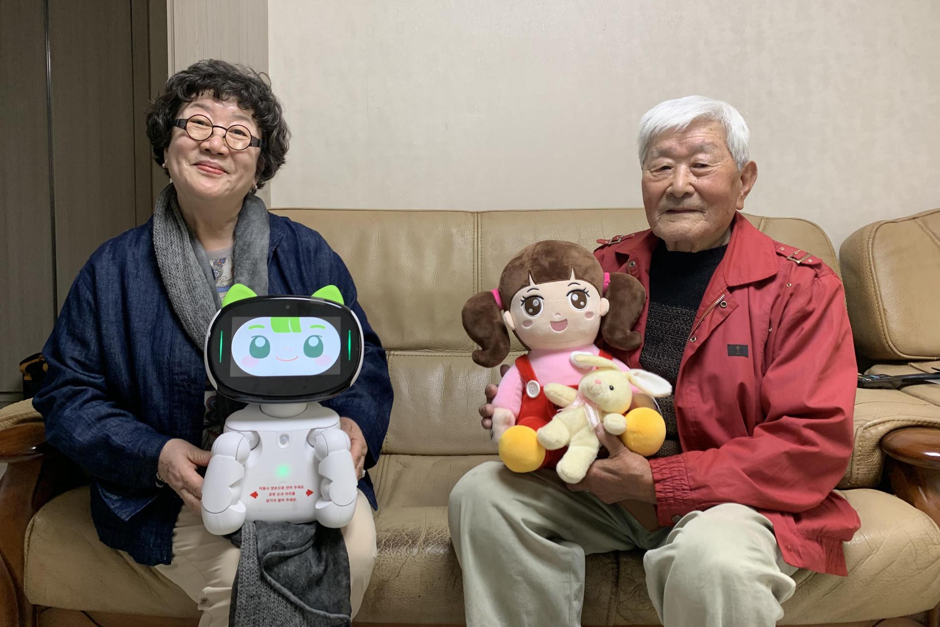 Lee Ha-seon y An Sang-ik sosteniendo el robot Dasomi y la muñeca Chorongi. 