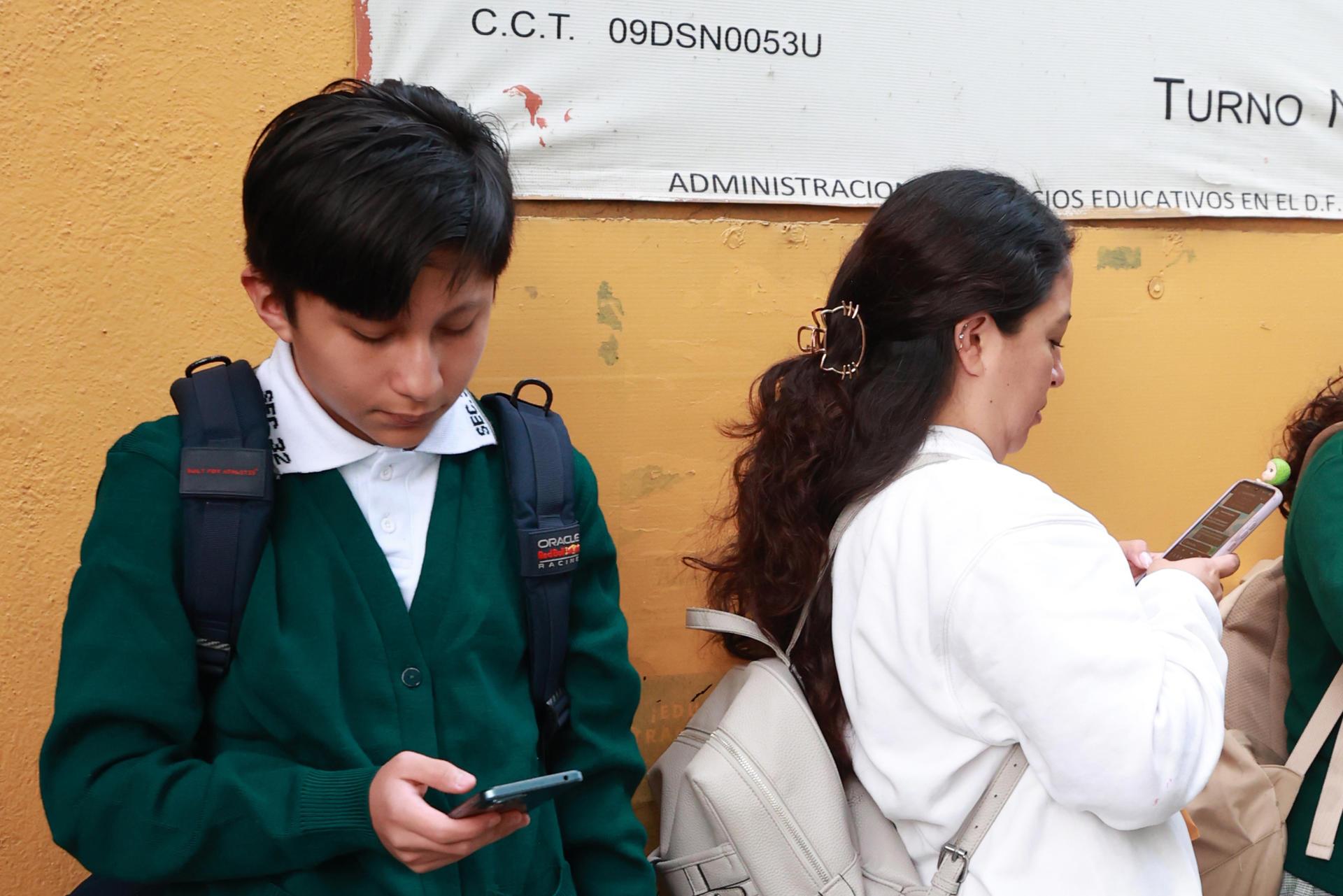 Un estudiante de secundaria usa el celular.